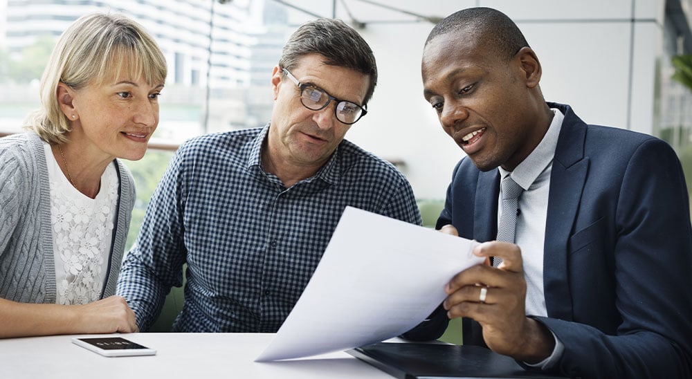 Advisor and client couple looking at document