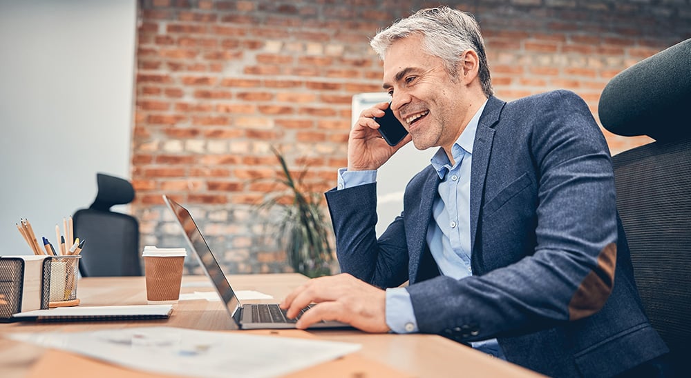 0944  Businessman smiling while on the phone and working on his laptop