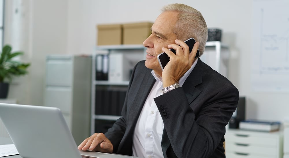 Businessman talking on the phone while working at a computer