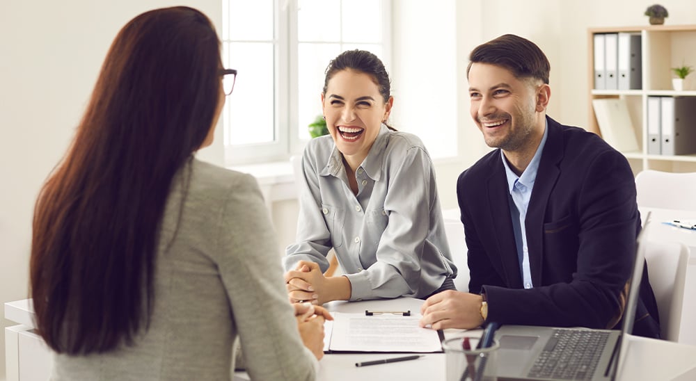 A female lender helping clients with in-home document signing at their home