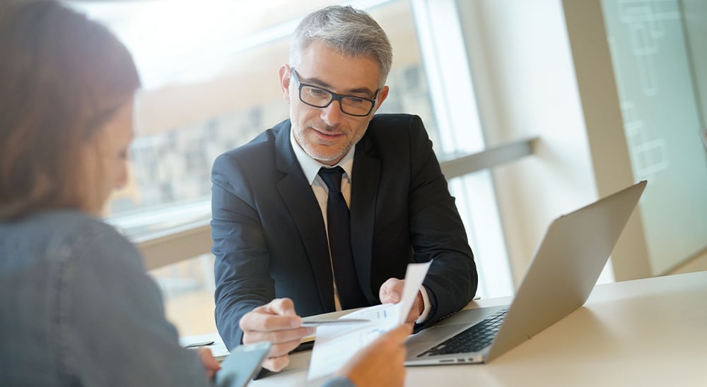 A male lender reviewing refinance documents with a client in his office