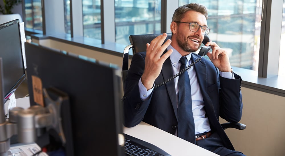 A male lender sitting at his desk talking on a phone
