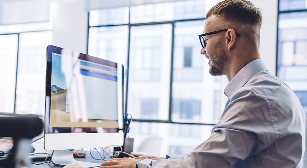 Businessman working on a desktop computer in a brightly lit office