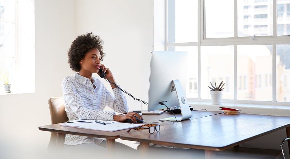 Business woman sitting in a bright office and talking on the phone