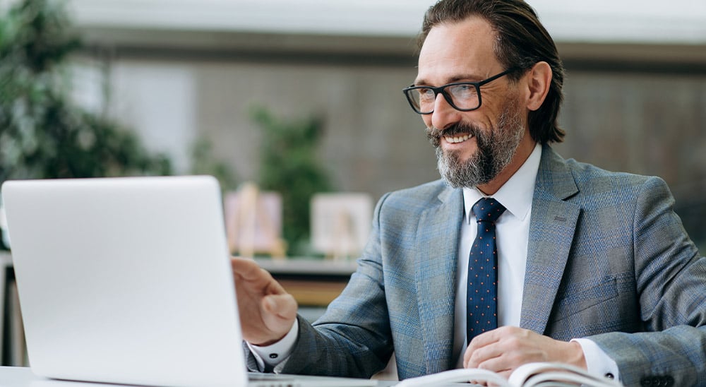 Man with suit and glasses on laptop