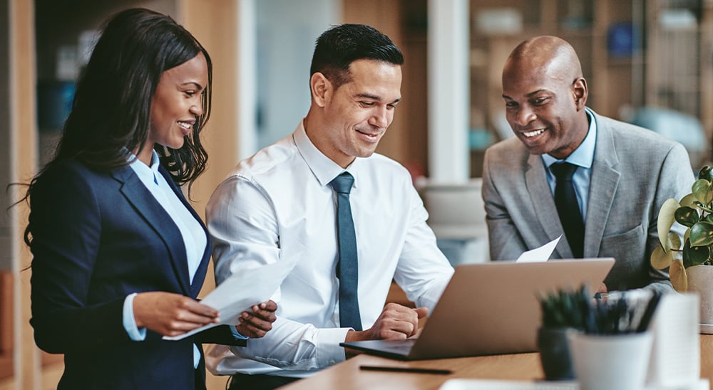 Three professionals looking at a computer