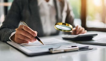 legal professional looking through documents with a magnifying glass