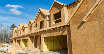 a row of suburban houses under construction, at the framing stage