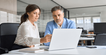 two legal professionals consult information on a laptop computer