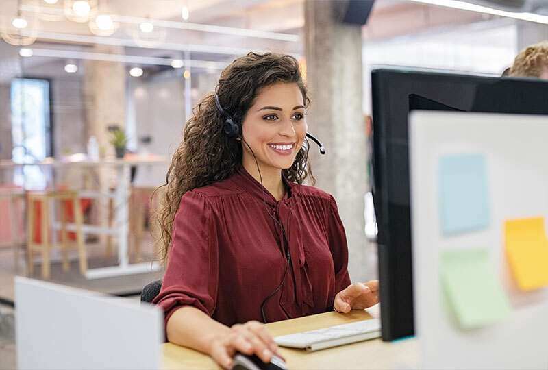 Woman assisting client through computer with headset