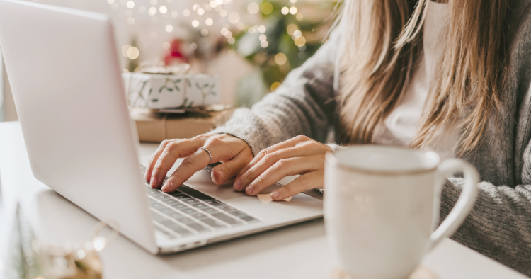 photo of a woman using her laptop with Christmas present and decorations around her